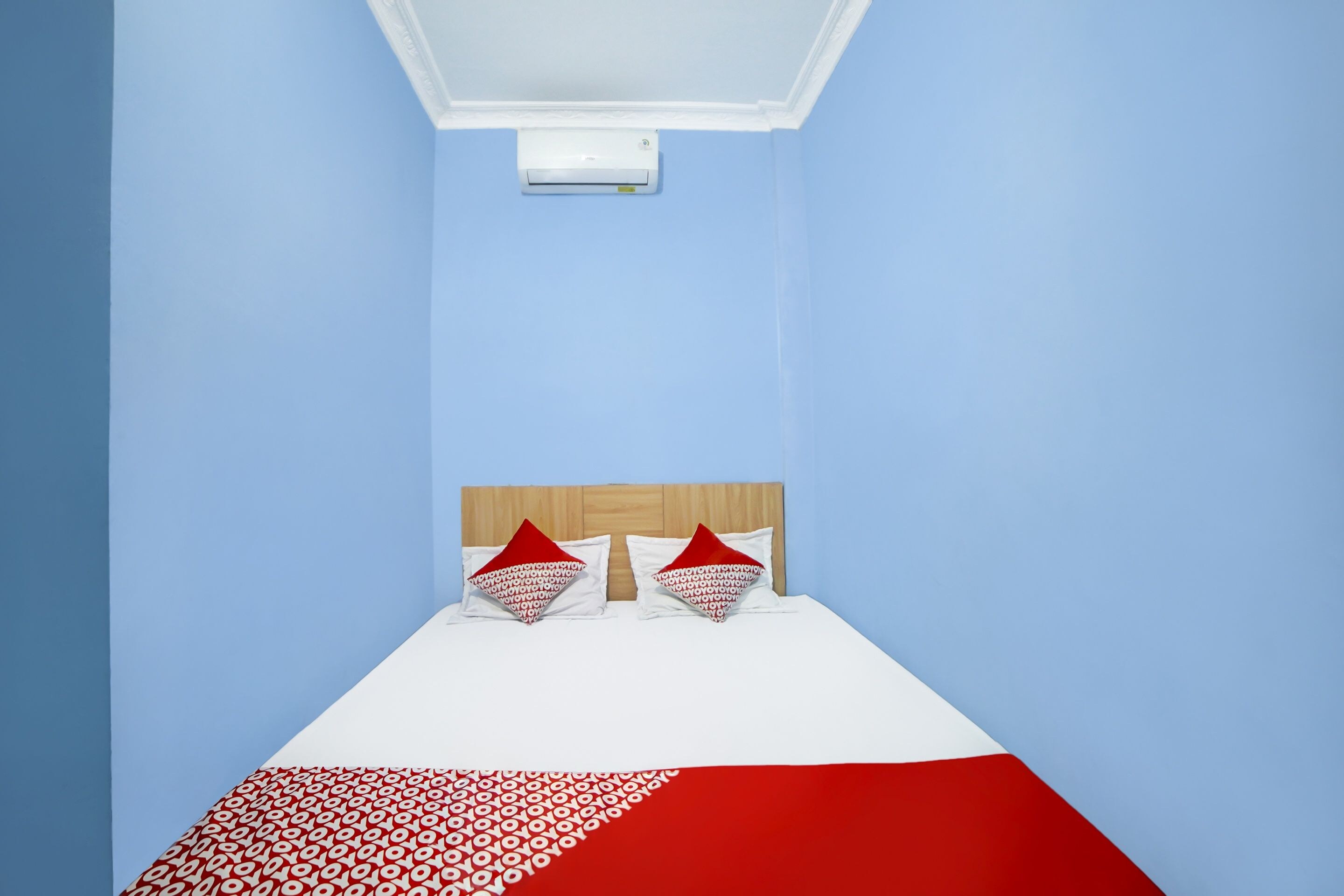 Ein Zimmer mit einem Bett, zwei Kissen, einem Kopfteil und einer an der Decke befestigten Klimaanlage.