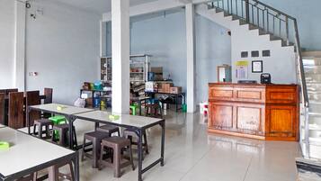 A spacious room with a staircase, tables, chairs, and a kitchenette area.