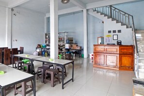 A spacious room with a staircase, tables, chairs, and a kitchenette area. - OYO 90922 Gurusinga Guesthouse (Medan)