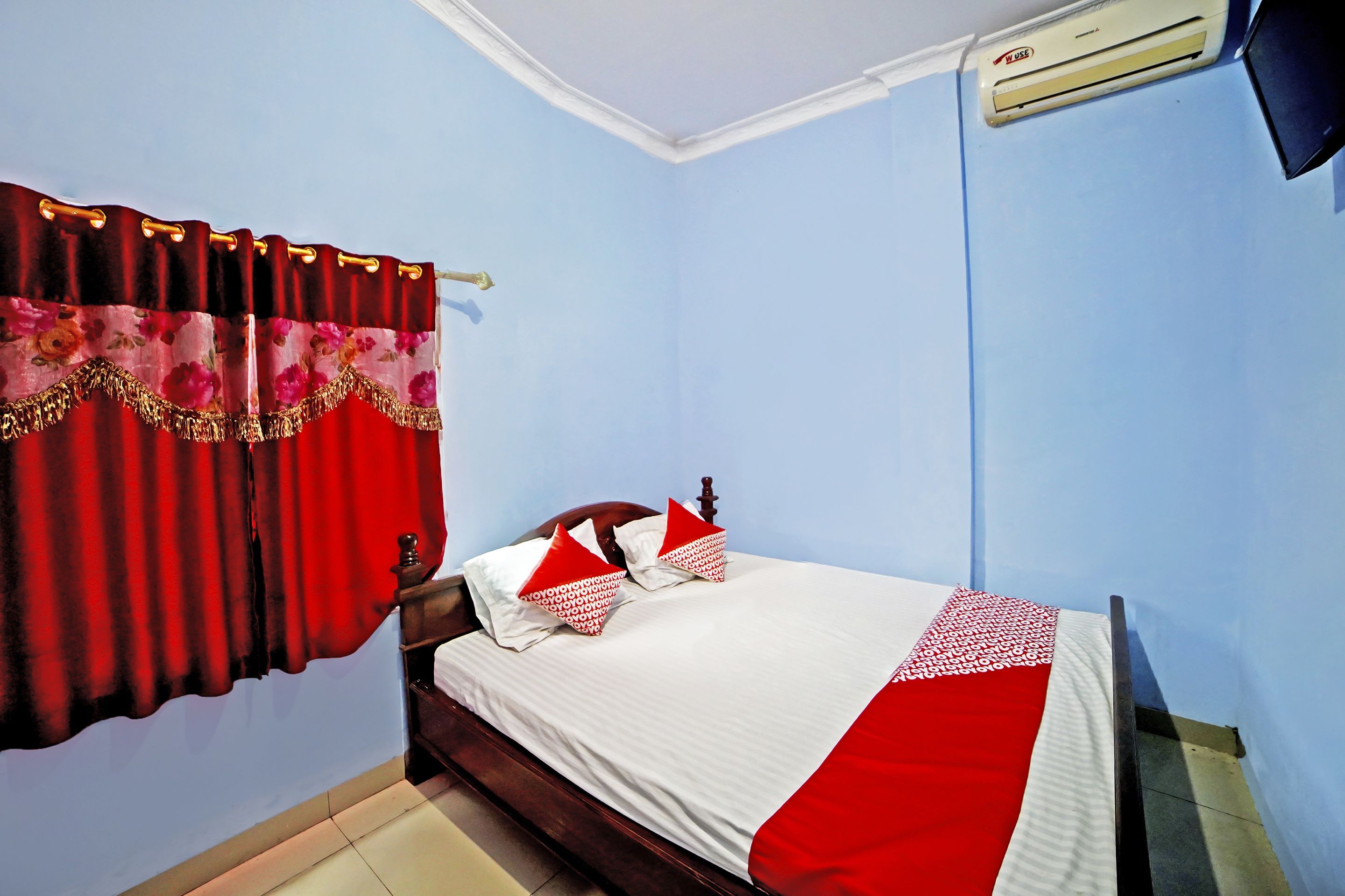 Ein Schlafzimmer mit einem Bett, roten Vorhängen und einem Deckenventilator.