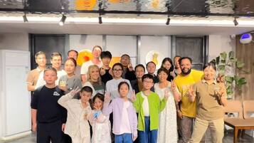 A group of people posing in a modern indoor setting with a large window and a ceiling with abstract art.
