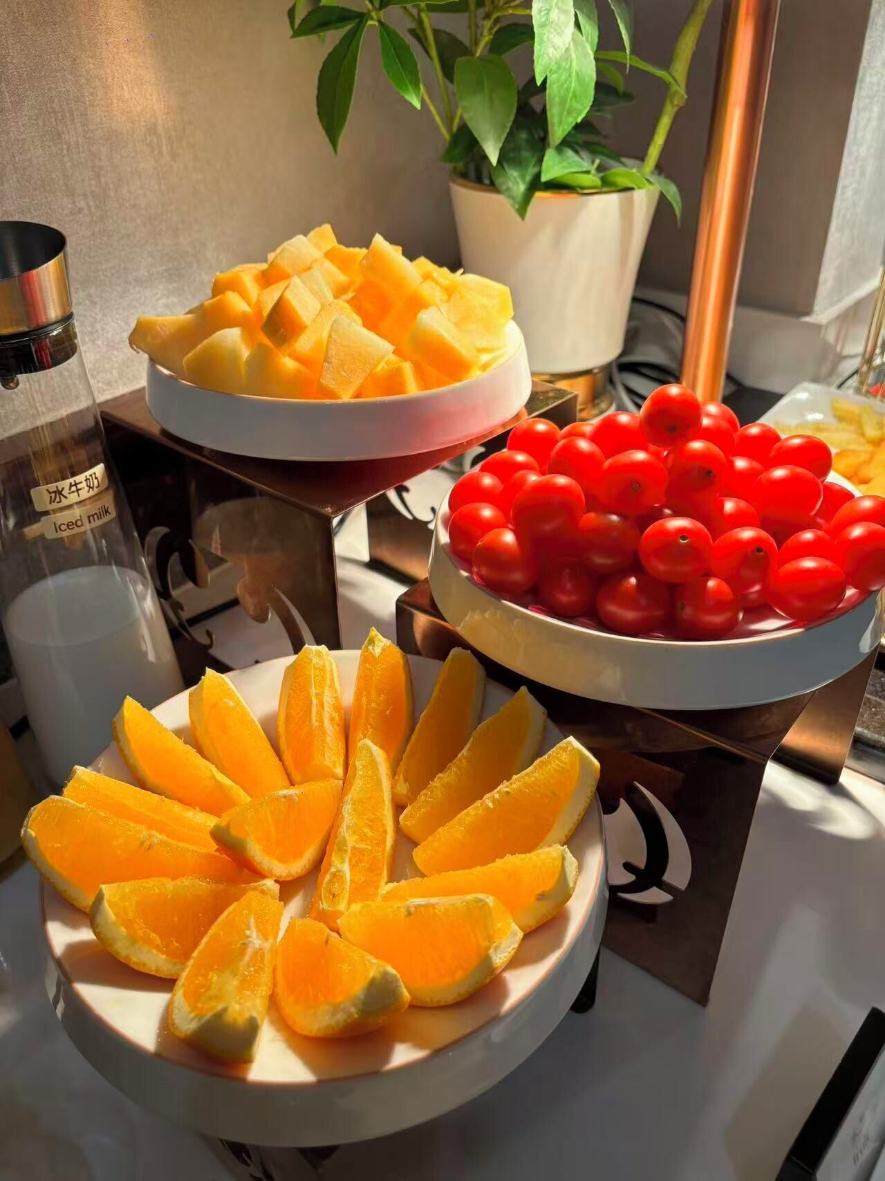 A table with three dishes: mango slices, cherry tomatoes, and orange segments.