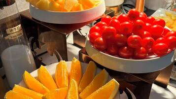 Een tafel met drie gerechten: mango plakken, kers tomaten en partjes sinaasappel.