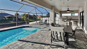 Ett takförsett utomhusområde med en swimmingpool, utemöbler och utsikt över området.