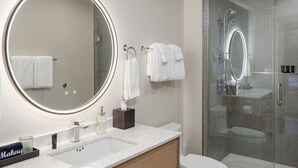 A modern bathroom with a large mirror, a sink, a toilet, and a glass-enclosed shower. - Johns - Graciously Appointed (Eastsound)