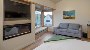 A modern living room with a large flat-screen TV, a fireplace, a sofa, and a painting on the wall. - Johns - Graciously Appointed (Eastsound)