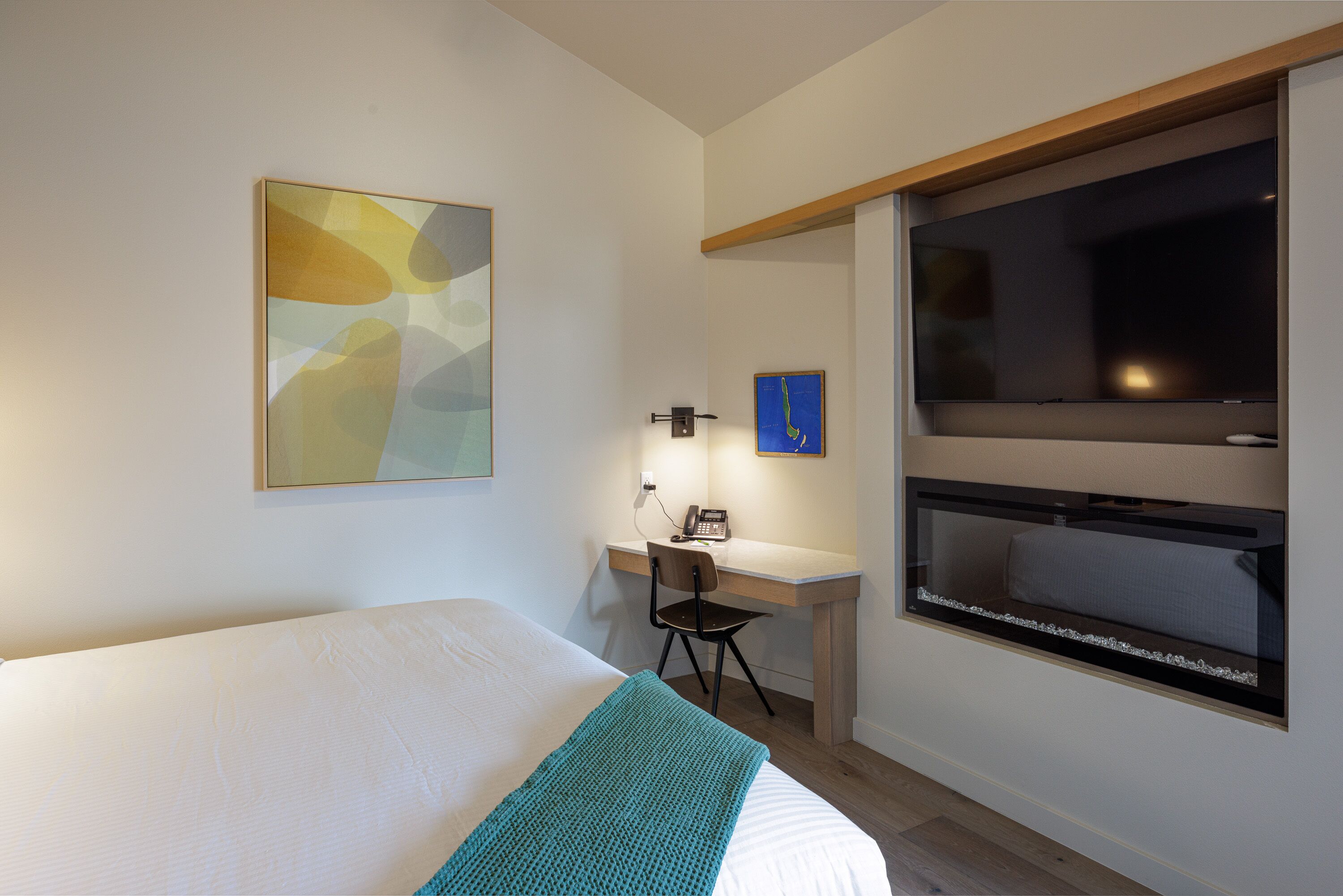 Una habitación de hotel con cama, escritorio, silla y un ventanal grande.