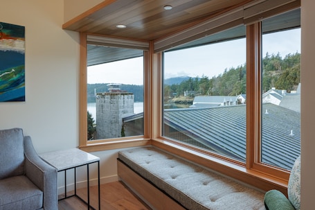 A room with a large window overlooking a residential area, a bench, and a small table.