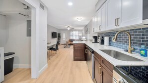 Una cocina moderna con armarios blancos, salpicadero de azulejos azules y un lavamanos de acero inoxidable.