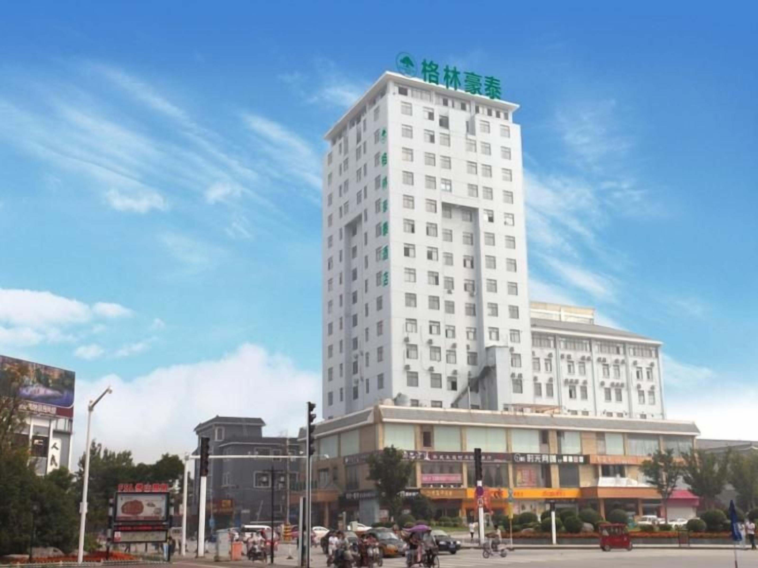 A multi-story hotel with a prominent green logo on the top.