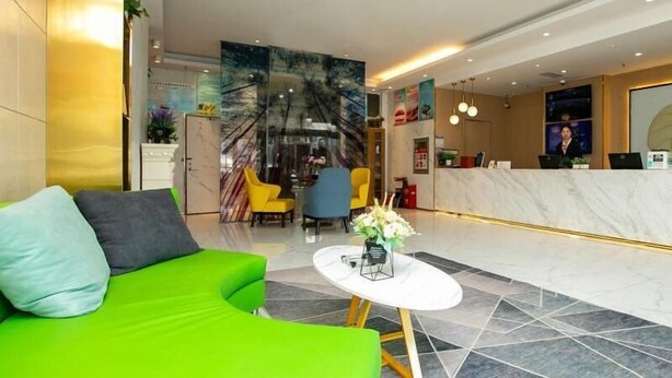 Un hall d’entrée moderne avec un canapé vert, un comptoir d’accueil et un grand tableau abstrait accroché au mur.