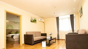 A modern living room with a sofa, a coffee table, and a bed in the background. - Greentree Inn Jiangsu Xuzhou Feng County Liubang Plaza Express Hotel (Xuzhou)