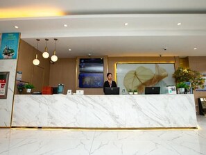 A hotel reception area with a marble counter, a receptionist, and a large leaf artwork on the wall. - Greentree Inn Jiangsu Xuzhou Feng County Liubang Plaza Express Hotel (Xuzhou)