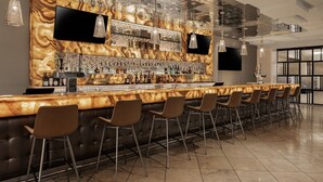 A modern bar area with a marble countertop, multiple bar stools, and a variety of bottles.
