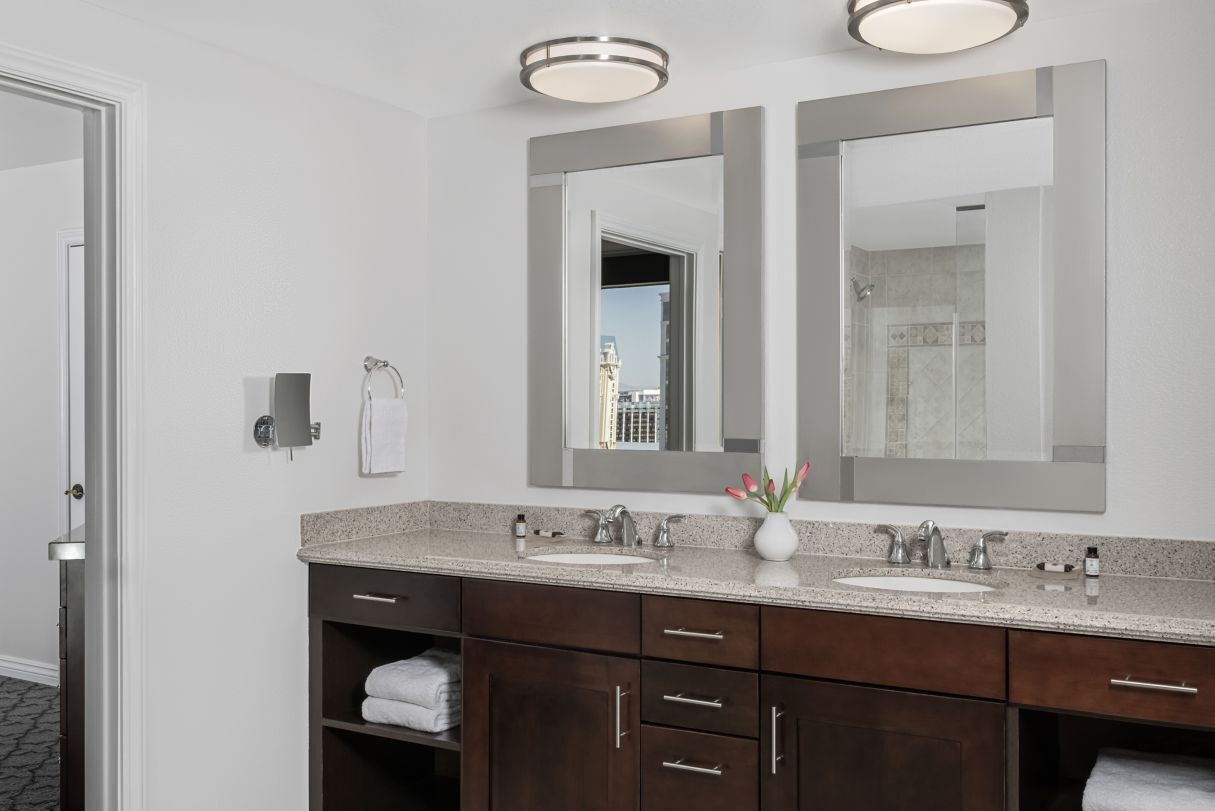 Une salle de bain moderne avec deux vasques, des meubles en bois foncé et un grand miroir.