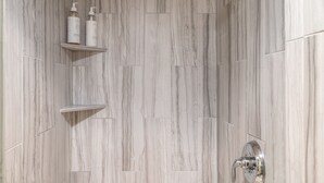 A bathroom with marble walls, a shower area, and two shelves holding bottles. - Mountainside Inn 421 1 Bedroom Hotel Room by Alpine Lodging Telluride (Telluride)