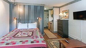A hotel room with a bed, a dresser, a TV, and a desk with a remote control. - Mountainside Inn 116 1 Bedroom Hotel Room by Alpine Lodging Telluride (Telluride)