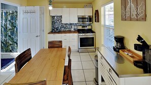 Una cocina con armarios blancos, una mesa de comedor de madera y una cafetera.