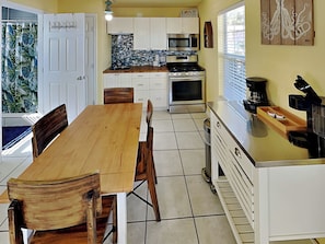 Una cocina con armarios blancos, una mesa de comedor de madera y una cafetera.