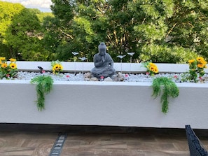 A serene outdoor garden with a statue, surrounded by sunflowers and greenery.