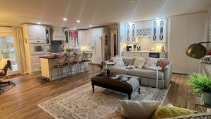 A modern living room with a sofa, coffee table, and a dining area with chairs.