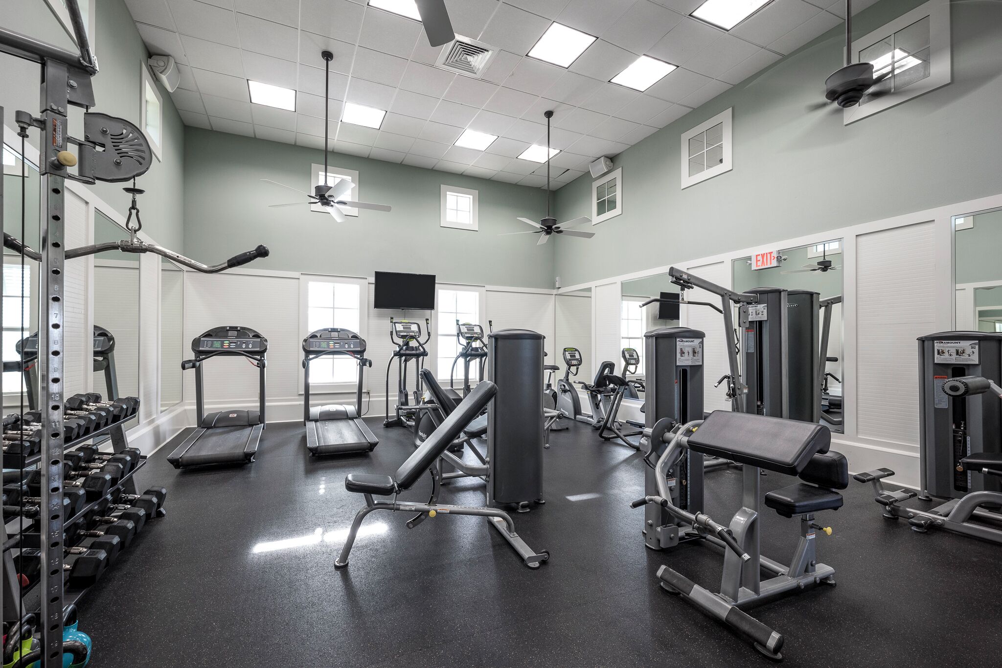 Et fitnesscenter med løbebånd, styrkemaskiner og håndvægte.