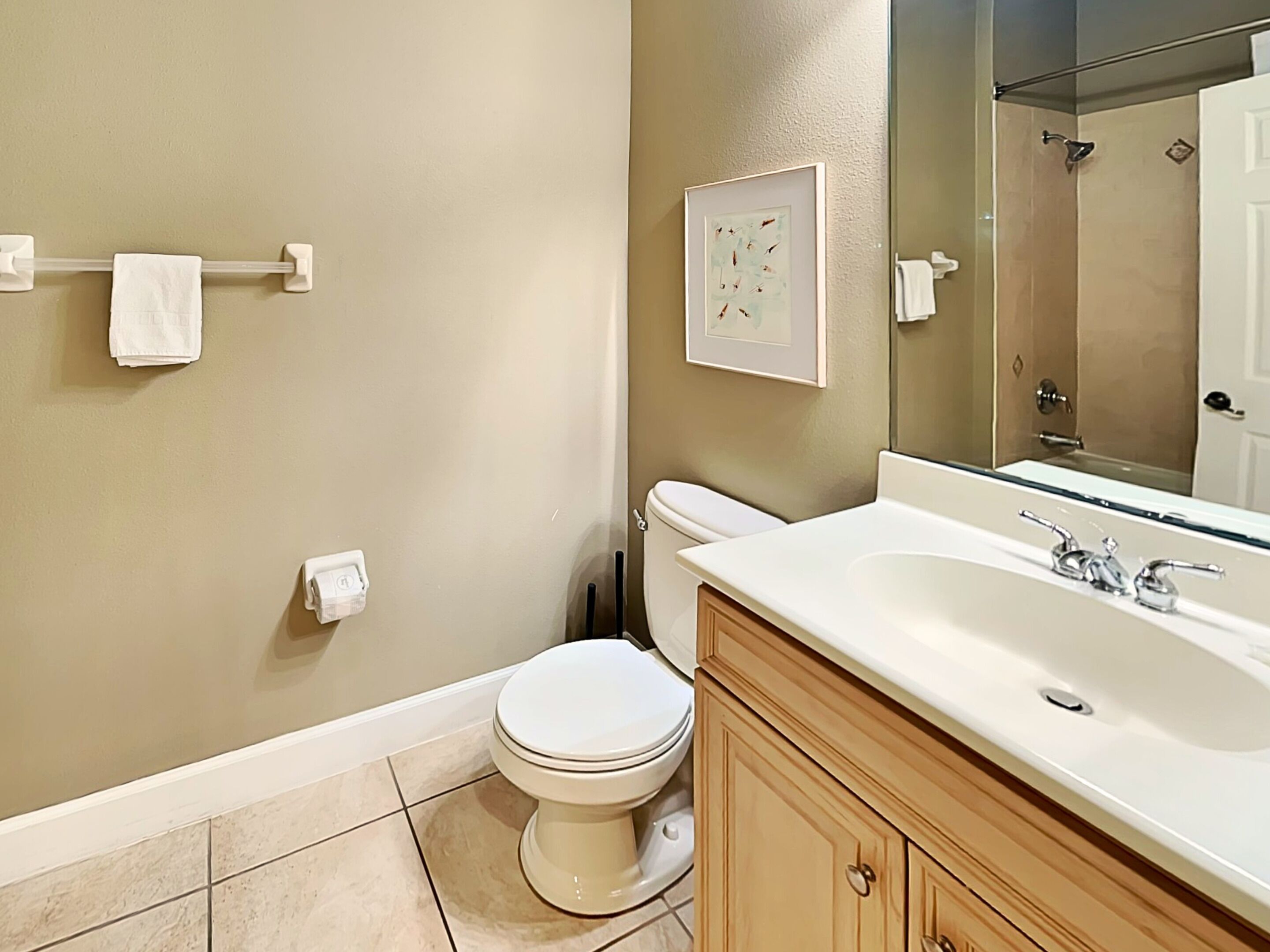 A bathroom with a toilet, sink, and mirror.