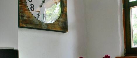 A kitchen with a clock, scale, and flowers on the counter.