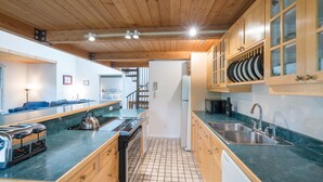 A modern kitchen with wooden cabinets, a large island with a stove and toaster, and a sink with a faucet. - Mountainside Inn 101 2 Bedroom Condo by Alpine Lodging Telluride (Telluride)