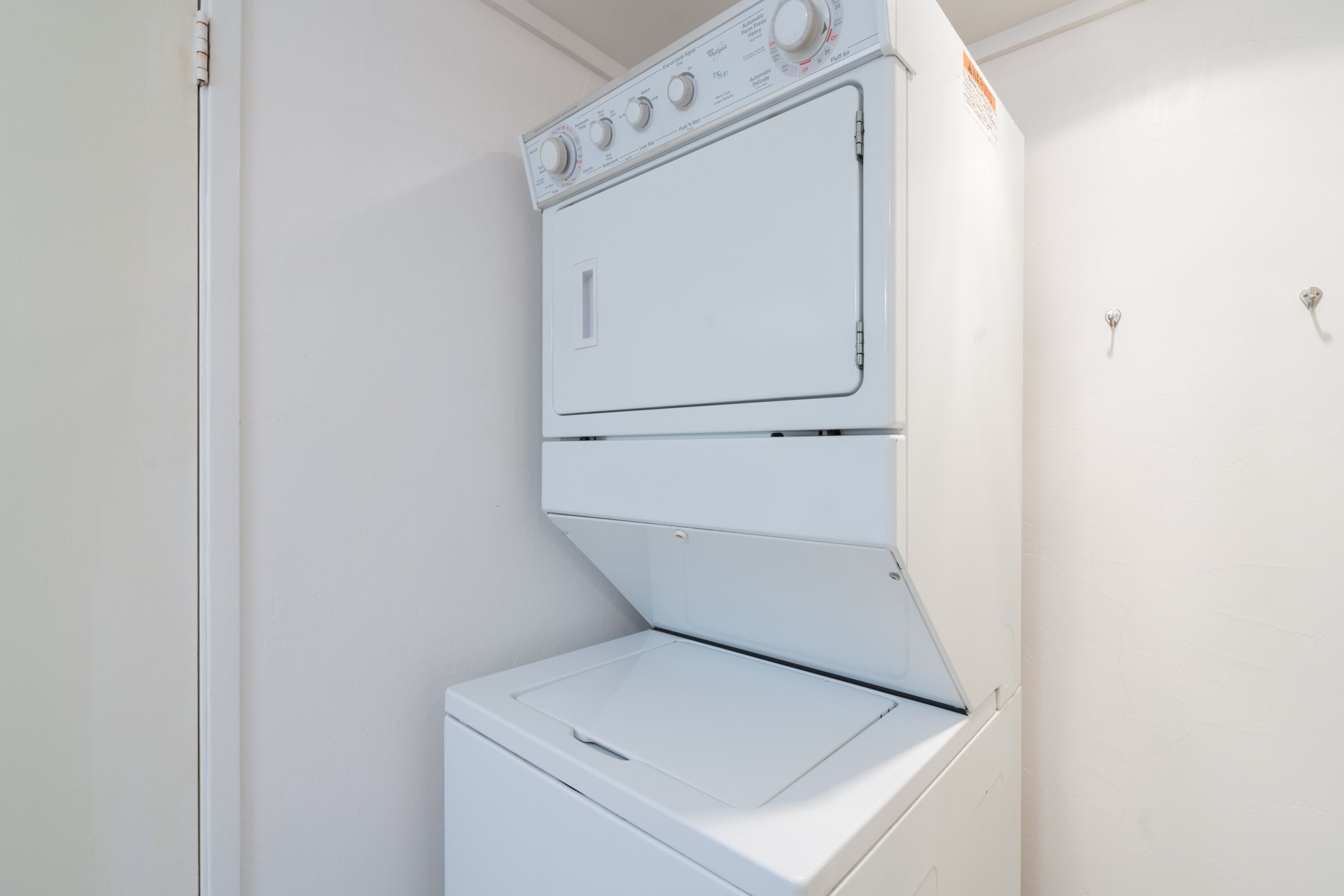A white wall-mounted washer and dryer unit with control knobs and a door.