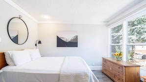 Een slaapkamer met een bed, een dressoir, een spiegel en een schilderij.