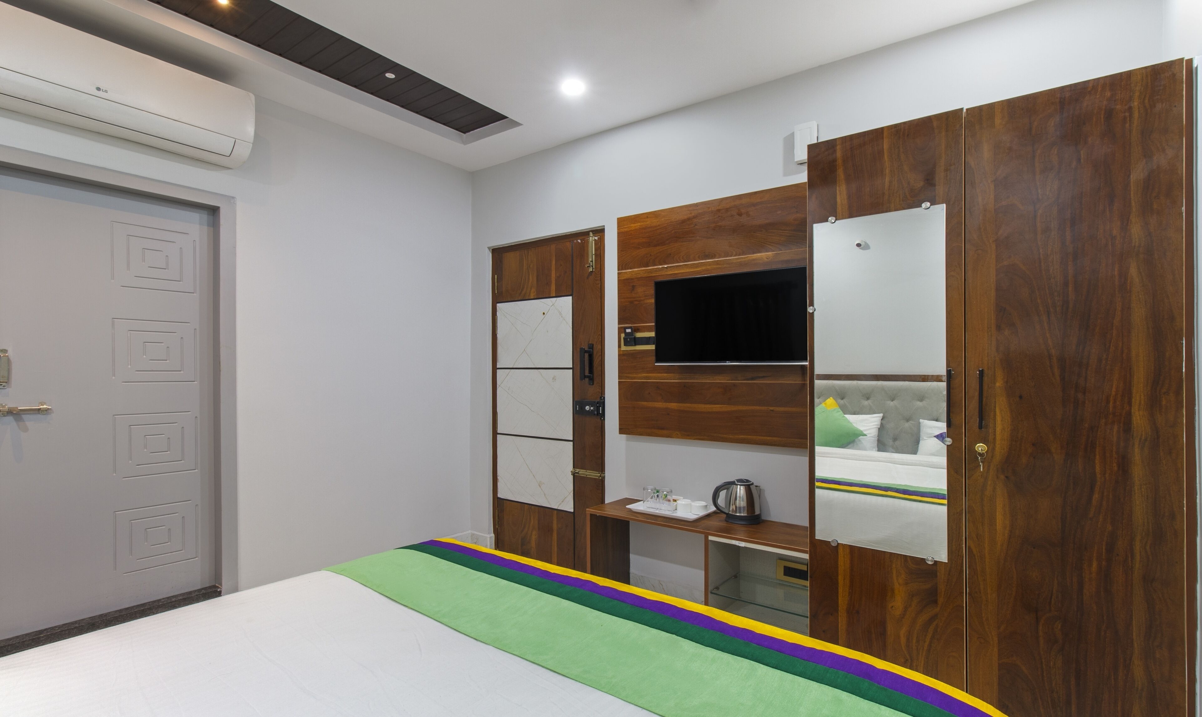 Ein Schlafzimmer mit einem Bett, einem Kleiderschrank und einem an der Wand befestigten Fernseher.