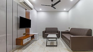 Una sala de estar moderna con un televisor de pantalla plana, dos sofás, una mesa de centro y un ventilador de techo.