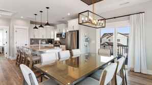 A modern kitchen with white cabinets, stainless steel appliances, and a large island with seating. - Osprey Isle: New Build | Private Pool | Rec Room (Corolla)