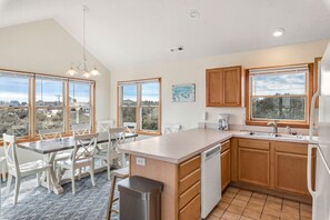 A modern kitchen with a large island, wooden cabinets, and a view of the countryside.