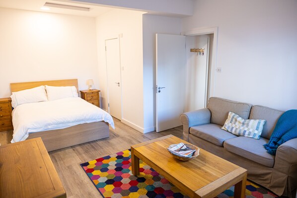 Une chambre à coucher avec un lit, une table de chevet et une petite table en bois.