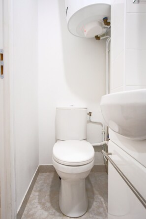 A small, clean bathroom with a toilet, sink, and white tiles.