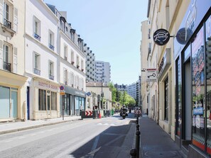 A street view with buildings, storefronts, and a clear sky.