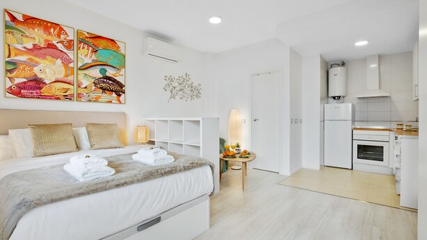 A modern hotel room with a large bed, a small table with breakfast, and a kitchen area. - Welcome Apartment, in the center of Malaga! (Málaga)