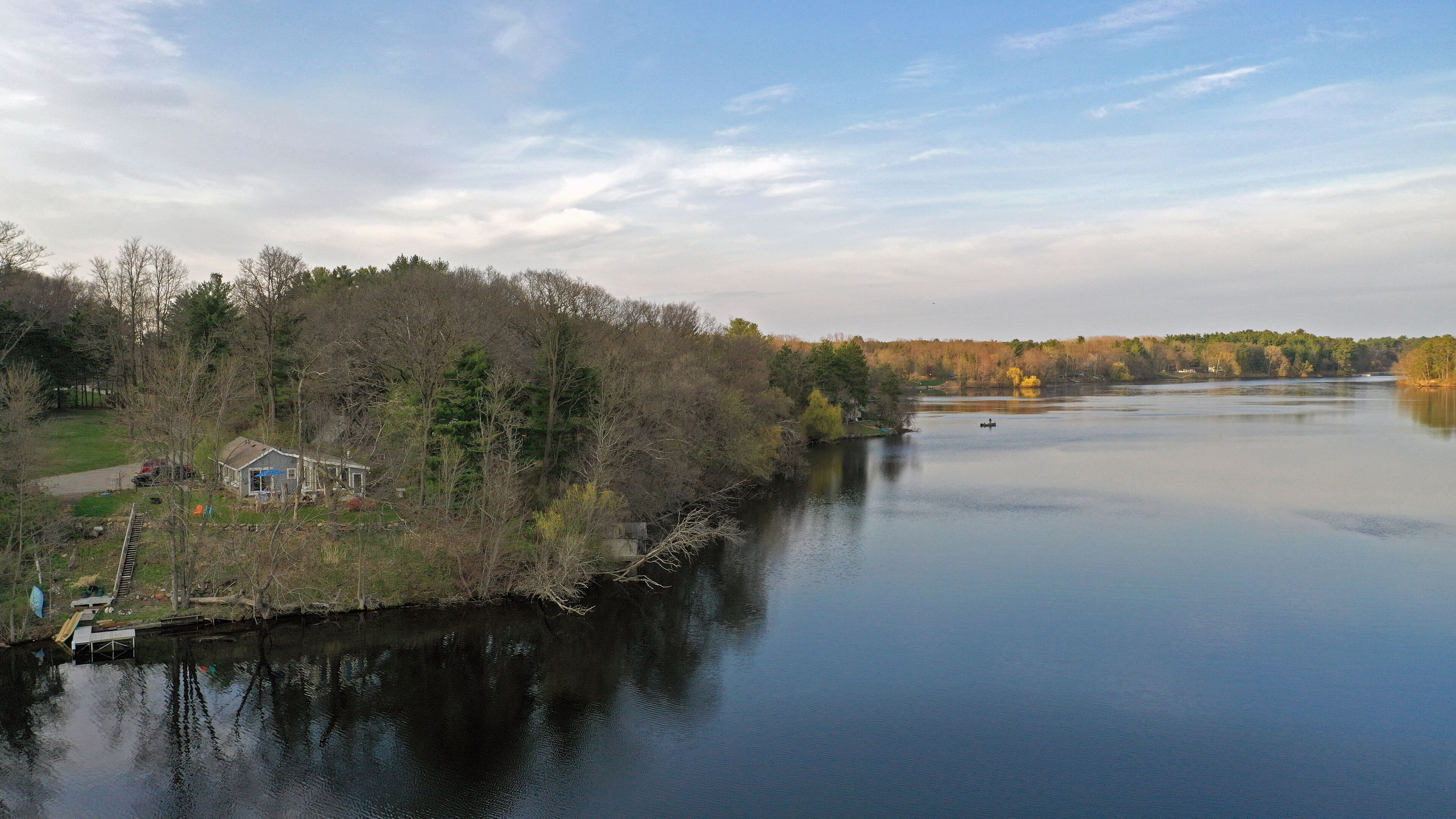 A lakeside property with a house, dock, and surrounding trees.