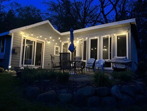 Ein Haus mit überdachter Terrasse, Sitzgelegenheiten im Freien und Lichterketten.