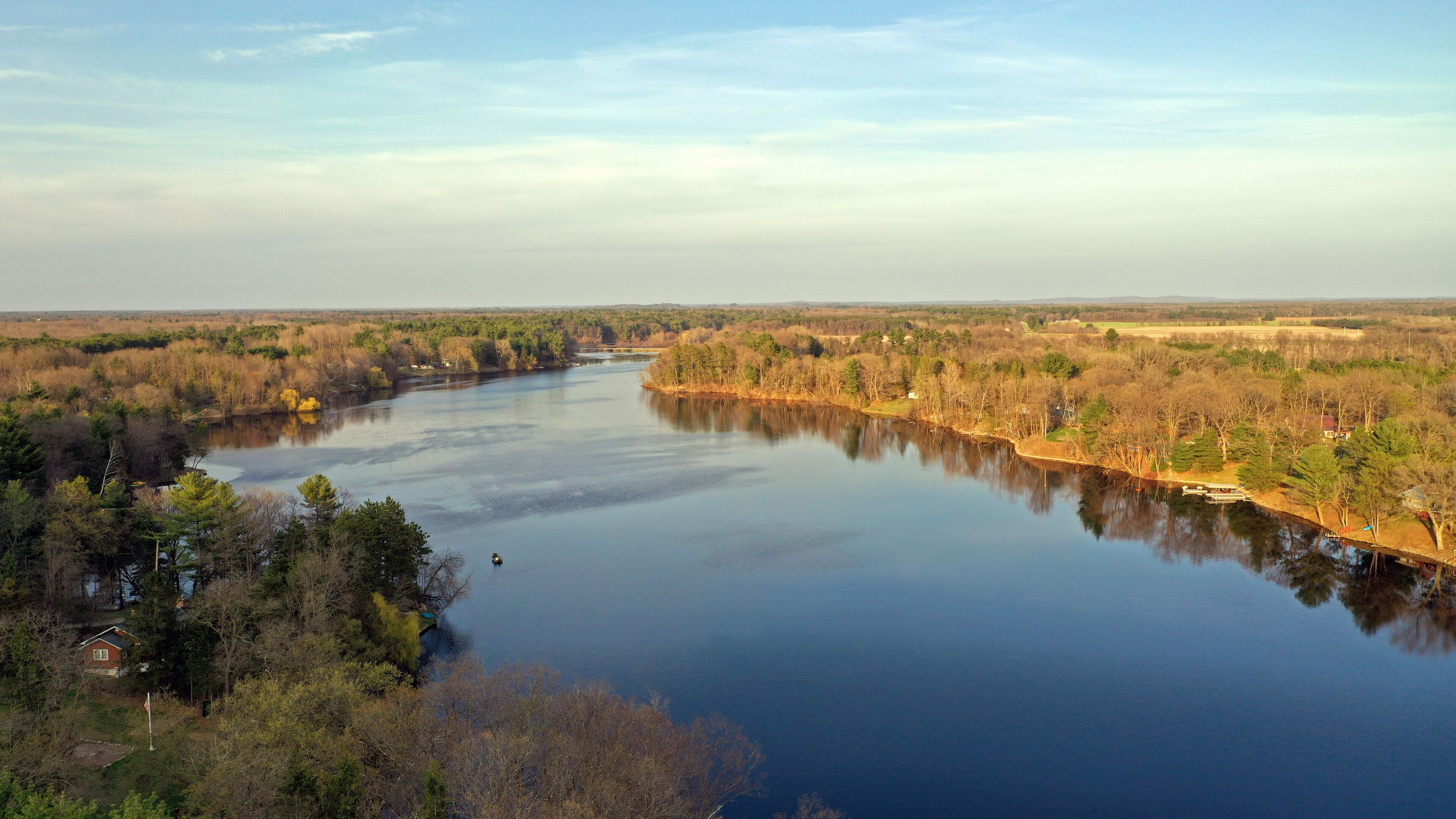 A river surrounded by dense forest and a few houses.