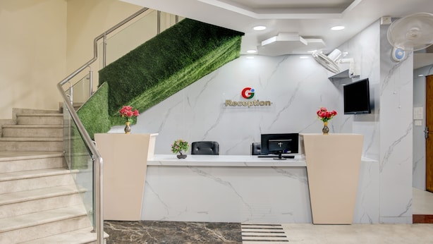 A reception area with a green artificial grass wall, a marble floor, and a staircase. - Treebo Golden Inn, 700 Mtrs From Promenade Beach (Puducherry)