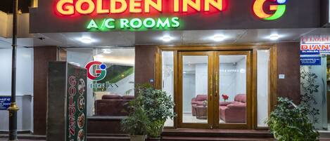 The exterior of a hotel named Golden Inn with A/C rooms, a reception area, and a visible entrance with a glass door.