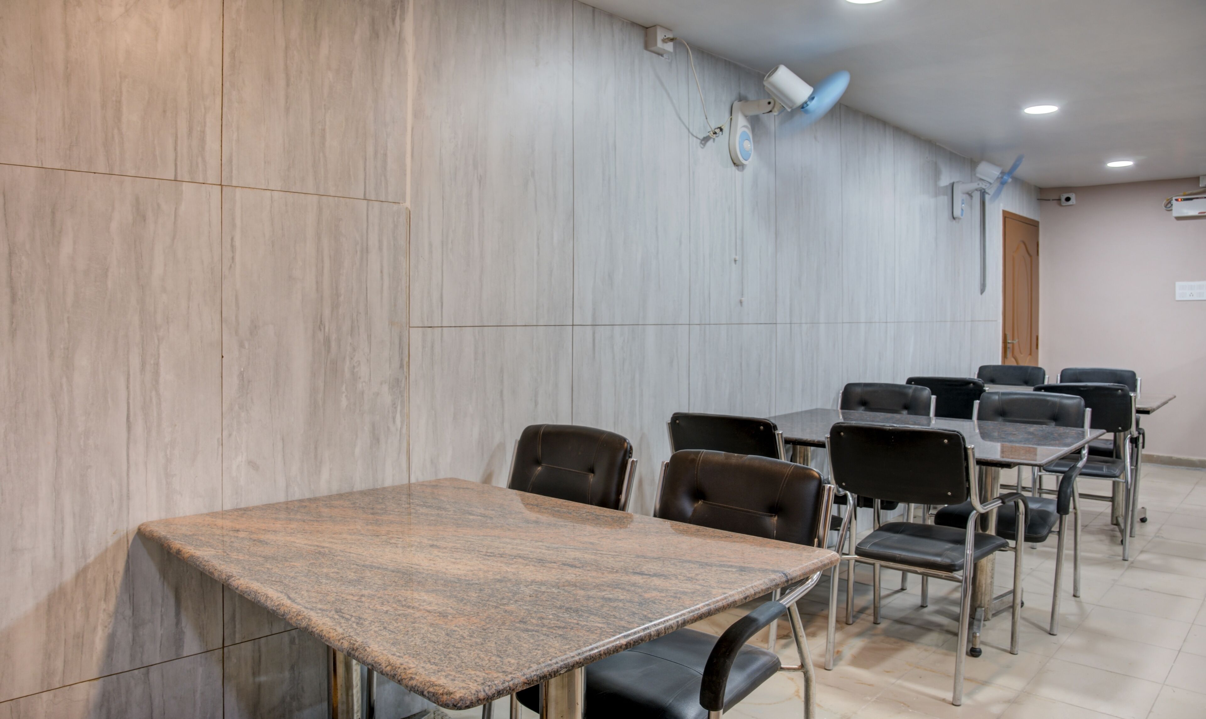 A conference room with a marble wall, a wooden table, and black chairs.