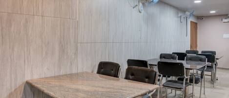 A conference room with a marble wall, a wooden table, and black chairs.