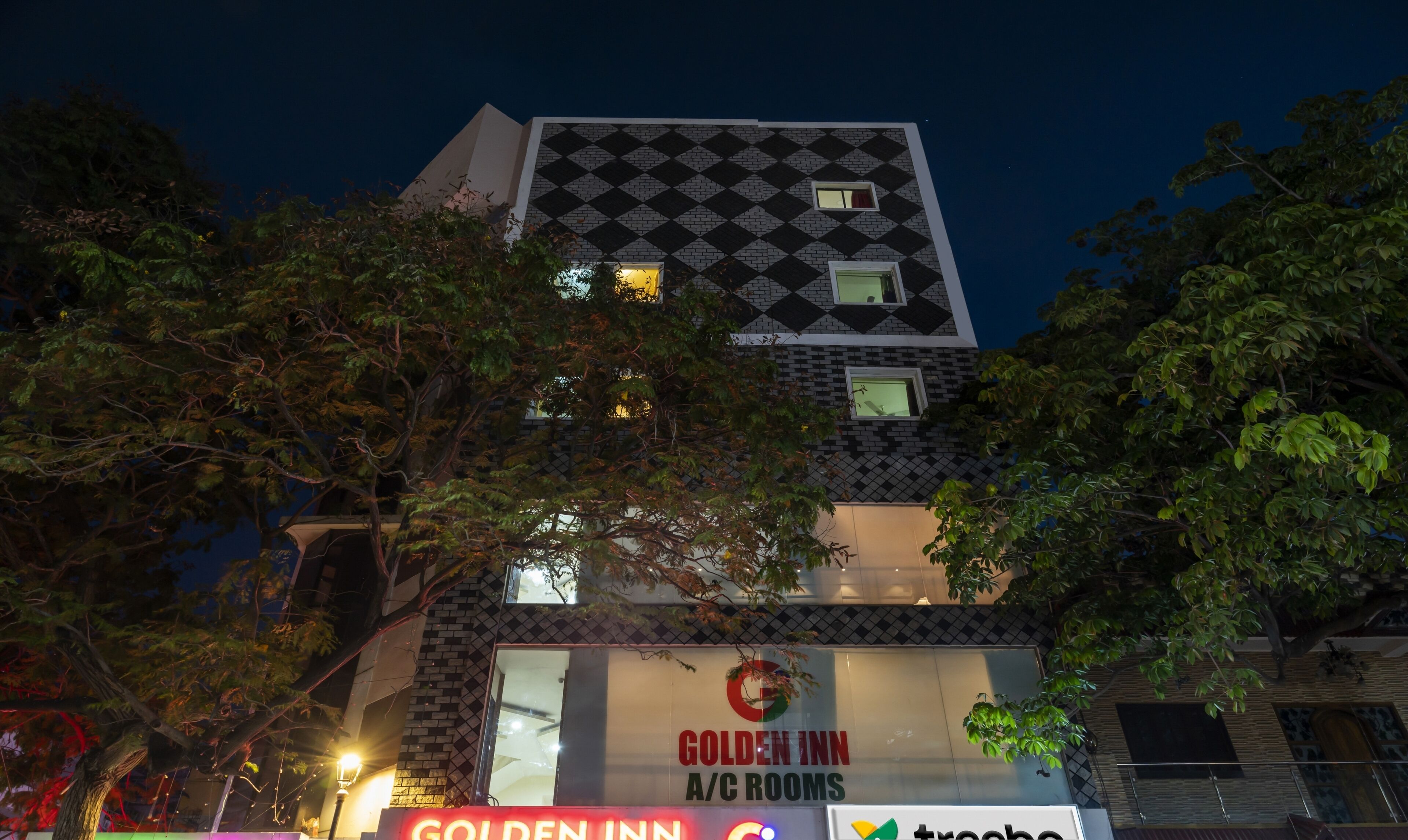 Un bâtiment à la façade à carreaux et portant une enseigne indiquant « Golden Inn, chambres climatisées ».