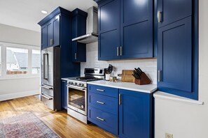 Une cuisine moderne avec des meubles bleu foncé, des appareils en acier inoxydable et un plancher en bois.