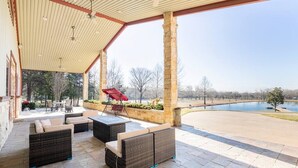 A covered patio area with outdoor furniture, a pool, and a view of the surrounding landscape. - Texas Ranch House with 5 bedrooms & Pond (Dallas)