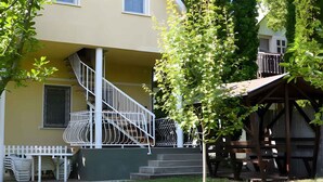 A two-story house with a white staircase, a covered porch, and a small outdoor seating area.